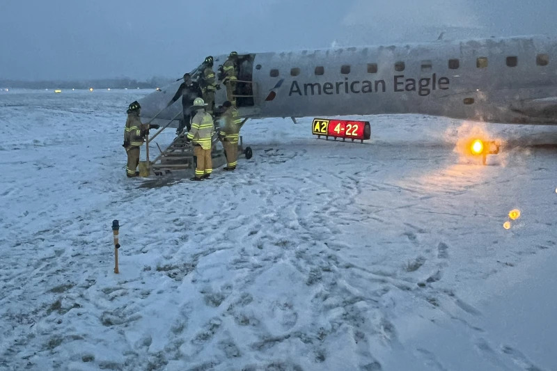 Nhân viên cứu hỏa của Sân bay Quốc tế Greater Rochester hỗ trợ hành khách rời khỏi chiếc máy bay của American Airlines trượt khỏi đường lăn đầy tuyết ngày 18/1. (Ảnh: AP)