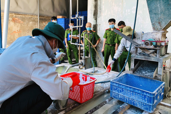 Cán bộ Đồng Nai lấy mẫu nước thải khu vực máy xay nghiền bóng đèn - Ảnh: Tuổi trẻ