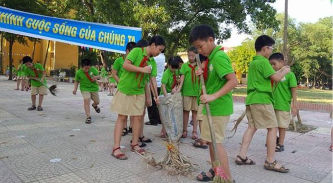 Các em học sinh tiểu học dọn dẹp vệ sinh môi trường