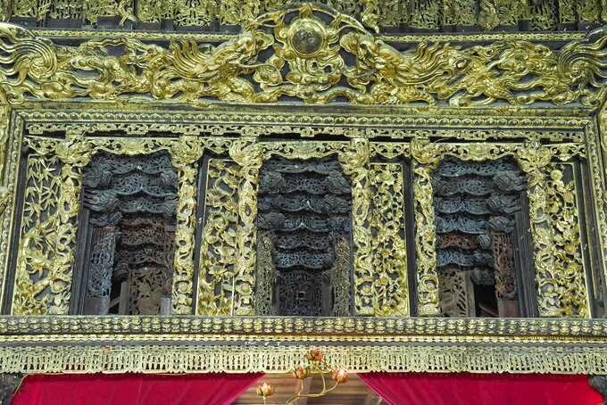 Tầng trên cùng khắc 9 đồ thờ cúng nên được gọi là bức hoành phi cửu sự. Tầng ở giữa là cửa võng, mỗi cửa võng có một đầu rồng bằng sành.