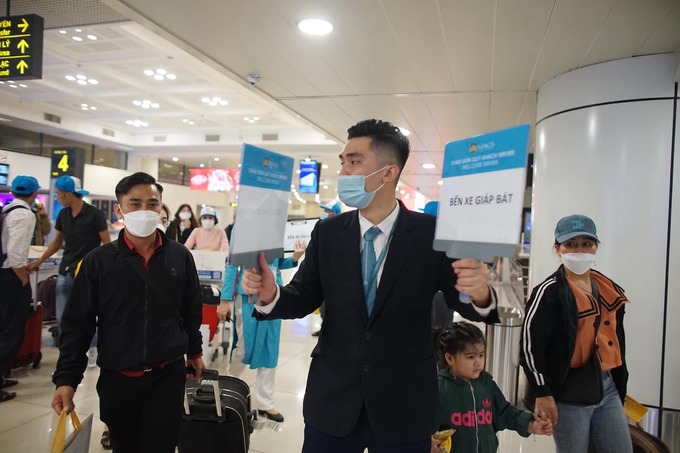Nhân viên Vietnam Airlines hỗ trợ người lao động di chuyển ra xe từ sân bay Nội Bài về các bến trung chuyển để đi tiếp về địa phương quê nhà. Ảnh: Chau Nguyen Viet