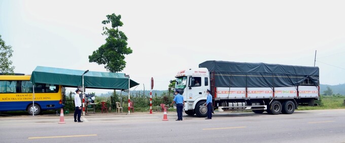 Thanh tra giao thông Quảng Nam ra hiệu lệnh dừng xe kiểm tra tải trọng trên tuyến đường QL14 B (Ảnh T. Hùng)