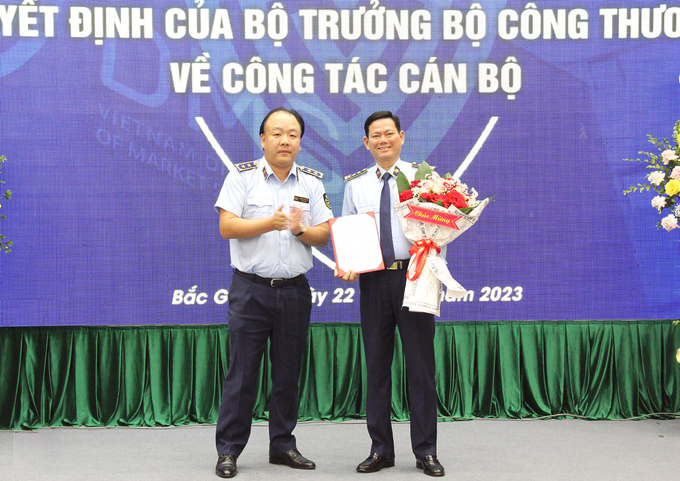 Tổng Cục trưởng Tổng Cục QLTT Trần Hữu Linh trao Quyết định và tặng hoa chúc mừng đồng chí Chu Thanh Hiến.