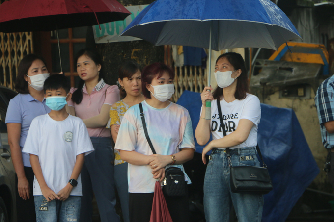 Những nét mặt lo lắng của phụ huynh chờ đợi dưới mưa khi con em vào phòng thi