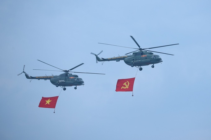 Các biên đội trực thăng vũ trang thuộc Quân chủng Phòng không - Không quân, Quân đội nhân dân Việt Nam mang theo cờ Đảng, cờ Tổ quốc Việt Nam bay qua sân vận động Điện Biên