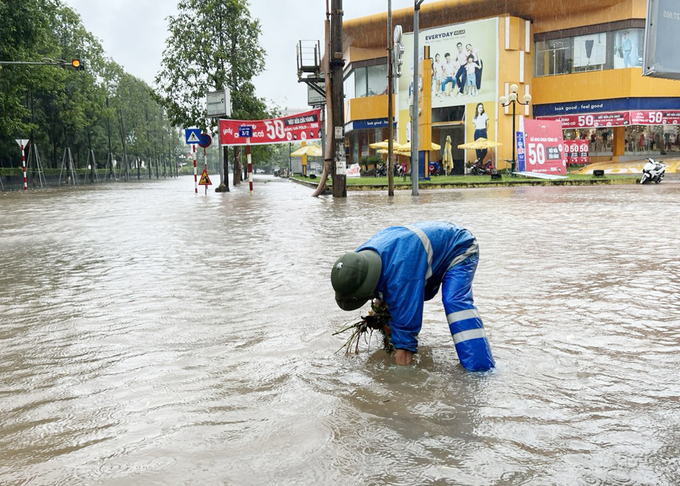 Công nhân Công ty cổ phần Quản lý công trình đô thị Bắc Giang kiểm tra hệ thống thoát nước toàn, vớt rác đọng ở các cửa hố ga, mở cửa thu nước ở những điểm ngập sâu. (Ảnh: BBG)