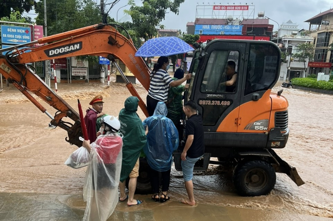 Những chiếc máy xúc được lực lượng chức năng điều tới cũng sẵn sàng đưa người dân băng qua điểm ngập úng