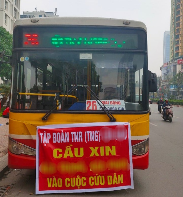 Chiếc xe lạ với tấm băng rôn chắn trước nhóm khách hàng biểu tình.