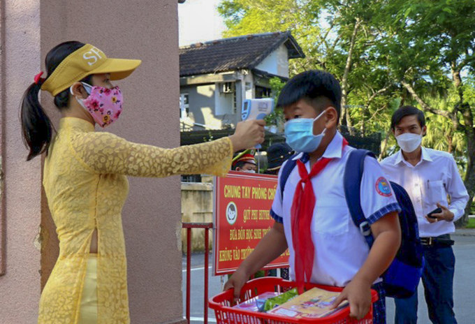 Ngày đầu tiên đi học trở lại, giáo viên trực tiếp đo thân nhiệt hướng dẫn sát khuẩn cho các em trước khi vào lớp (Ảnh:TS)