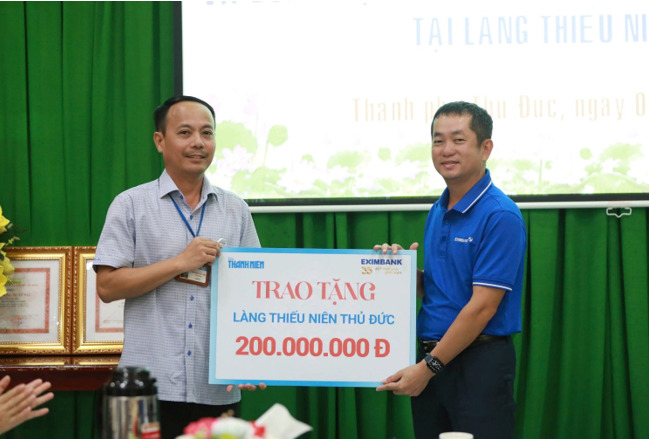 Ông Nguyễn Hướng Minh, Phó Tổng Giám đốc Eximbank (bên phải) trao quà cho đại diện Làng Thiếu niên Thủ Đức.