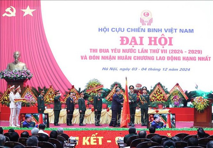 Tổng Bí thư Tô Lâm gắn Huân chương Lao động hạng Nhất lên lá cờ truyền thống Hội Cựu chiến binh Việt Nam - Ảnh: TTXVN