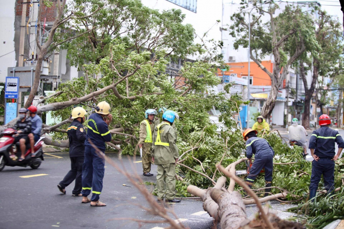 Người dân và lực lượng chức năng đang khẩn trương dọn dẹp vệ sinh, di dời cây xanh bị ngã đổ trên đường để tránh bị ùn tắc giao thông.