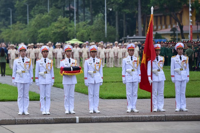  Các chiến sĩ tiêu binh cầm Quốc kỳ có gắn băng tang tiến vào đài kỳ.