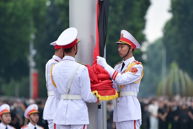  Sau đó lá Quốc kỳ gắn băng tang bắt đầu được kéo lên cột cờ.