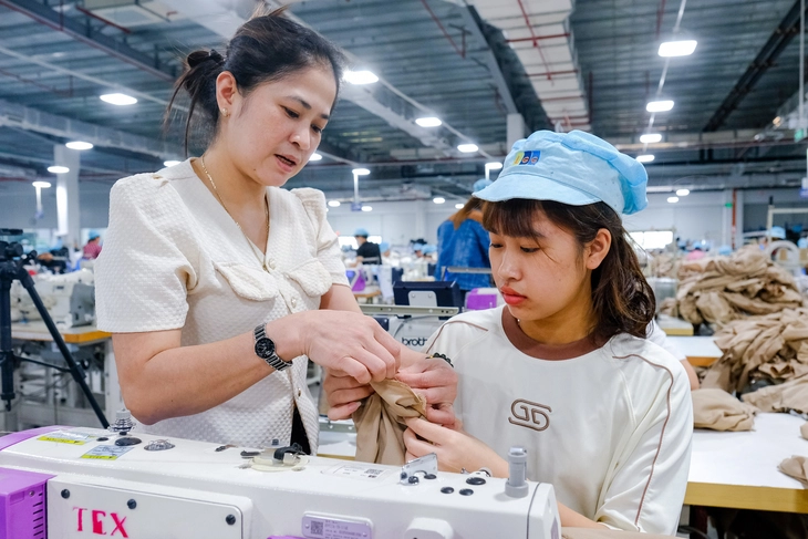 Công nhân trẻ được lao động có kinh nghiệm hỗ trợ, chia sẻ kinh nghiệm ngay trên bàn máy may tại Công ty cổ phần Dệt may Lạng Giang (Bắc Giang) - Ảnh: HÀ QUÂN