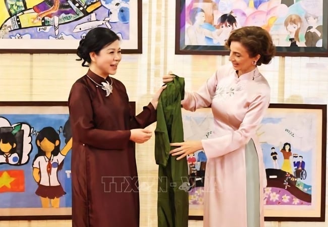 Phu nhân Tổng Bí thư, bà Ngô Phương Ly trao chiếc áo dài truyền thống tặng Tổng Giám đốc UNESCO Audrey Azoulay. Ảnh: TTXVN
