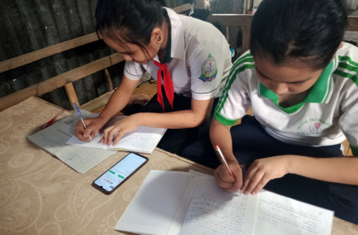 Hai học sinh ở Cần Thơ phải học online chung bằng một chiếc điện thoại để theo kịp chương trình của lớp. Ảnh: FPT