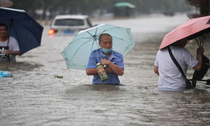 Người dân lội trong nước lũ ở Trịnh Châu, Trung Quốc. Ảnh: Reuters.