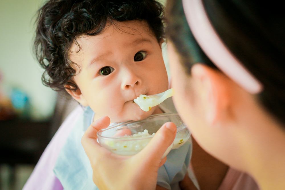curly-haired_asian_baby_being_fed_with_a_spoon