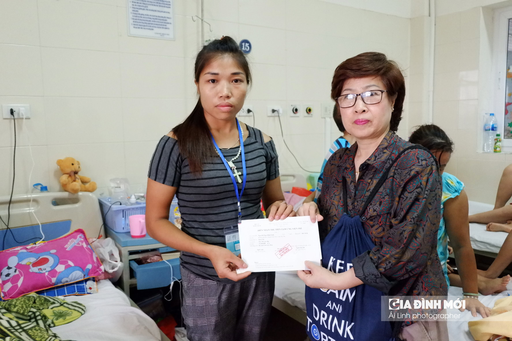 Chị Lý, mẹ bé Diệu Linh (bên trái) nhận số tiền 40 triệu đồng từ đại diện Gia Đình Mới