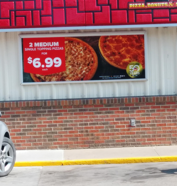   Poster quảng cáo ghi '2 pizza cỡ vừa có giá là 6.99 USD', nhưng dòng chữ nhỏ dưới cùng là 'trên một sản phẩm'  