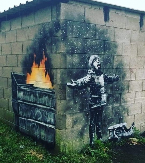   Tác phẩm mới của họa sĩ Banksy, nếu mới nhìn một bên tường bạn có thể nghĩ cậu bé đang bắt những bông tuyết, nhưng thật ra đó là tro bụi  