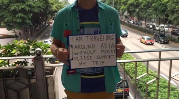   'Tôi đang đi du lịch vòng quanh châu Á không có tiền. Xin hãy ủng hộ cho chuyến đi của tôi' - Tấm biển được một thanh niên có vẻ khỏe mạnh giơ lên  