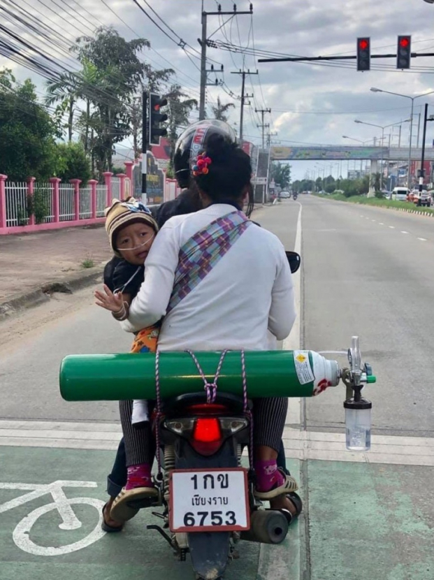   Cả gia đình cậu bé cùng bình oxy trên chiếc xe máy (Ảnh: Chirapat Pinkong)  