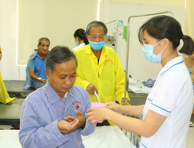   Bệnh nhân người Lao Siêng Bun Thăn đang được nhân viên y tế chăm sóc  