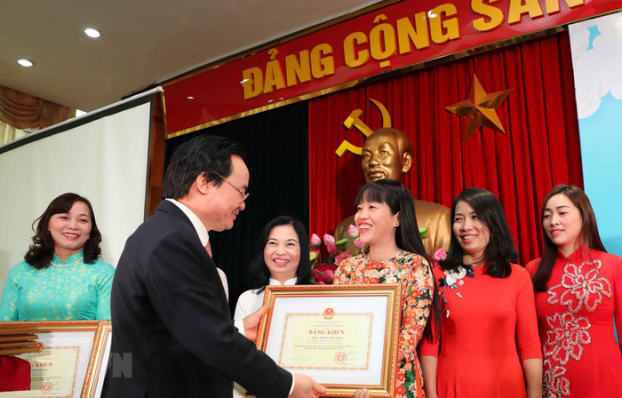   Bộ trưởng Phùng Xuân Nhạ tặng Bằng khen cho các giáo viên mầm non. Ảnh: TTXVN.  