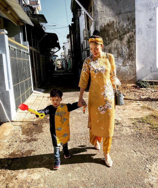   Dương Cẩm Lynh cùng con trai dạo phố trong bộ áo dài cách tân màu vàng nổi bật. Người đẹp cũng chọn băng đô cùng màu để giúp vẻ ngoài thêm trẻ trung hơn.  