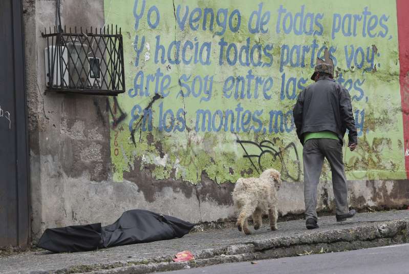   Người đàn ông cùng chú chó cưng của mình bước trên đường phố, bên cạnh là một túi đen chứa thi thể của một bệnh nhân COVID-19 ở Quito, Ecuador  