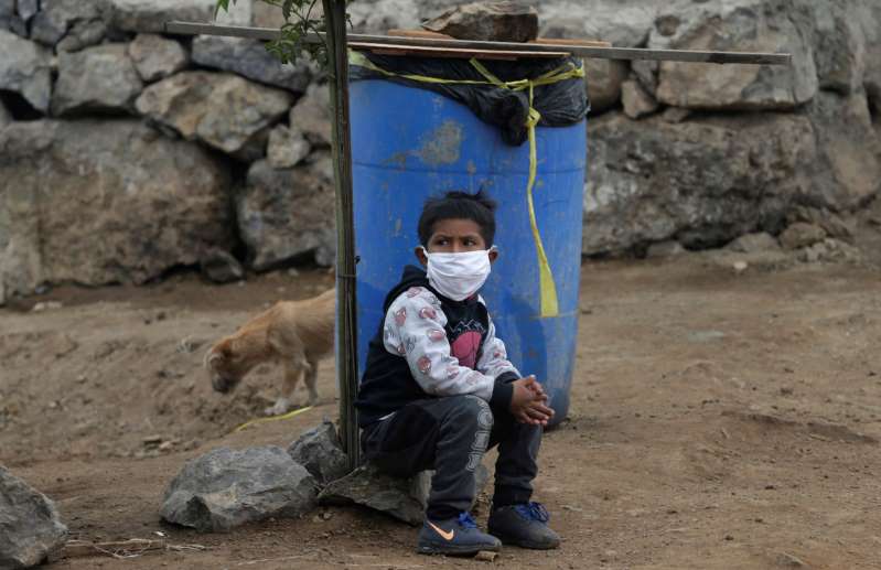   Một cậu bé đang ngồi chờ mẹ lấy đồ ăn từ thiện ở Lima, Peru  