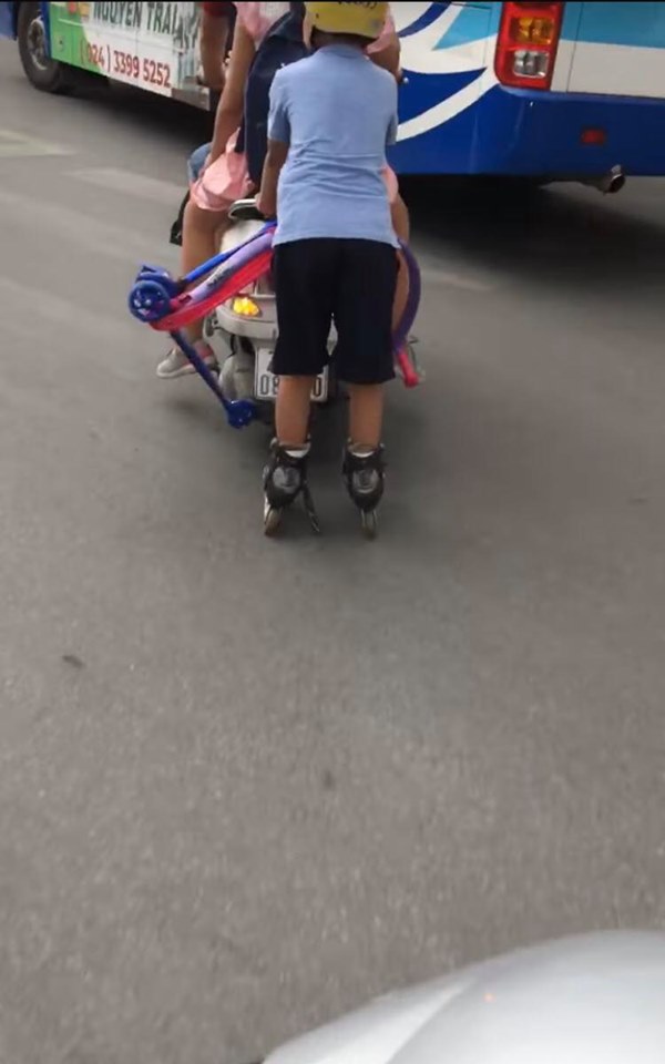   Cậu bé đi giầy trượt patin bám vào đuôi xe máy di chuyển  