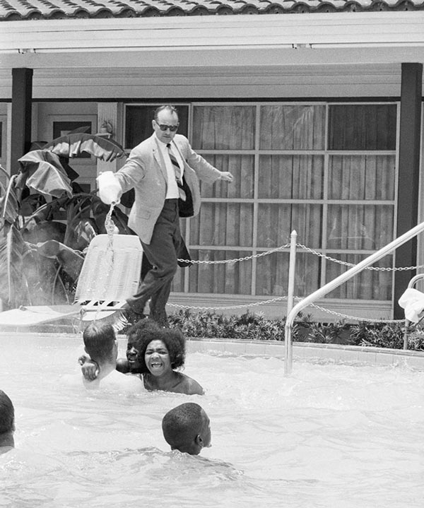   Người đàn ông trong bức ảnh không phải đang đổ nước xuống bể bơi để trêu đùa các bạn mà ông ta đang đổ axit để đuổi những người da trắng và da màu tham gia phong trào dân quyền khỏi nơi này. Ông ta là người quản lý khách sạn Monson Motor Lodge và bức ảnh được Horace Cort chụp vào ngày 18/6/1964.  