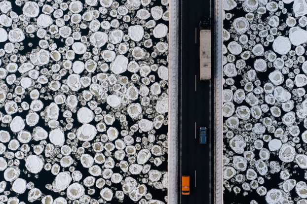   Dòng sông băng với những tảng băng trôi hình tròn nhường như bị tách đôi bởi cây cầu khi nhìn từ trên cao.  