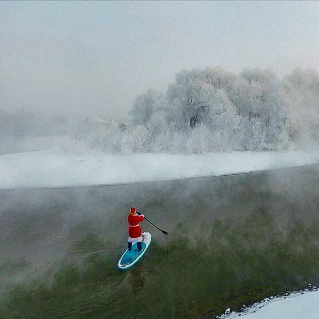   Một người trong trang phục Ông già Noel chèo thuyền trên mặt nước lạnh giá  