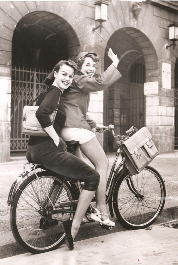   Hai cô học sinh này đang đạp xe về nhà để thay bộ quần áo bó sát và chiếc quần short ngắn vì chúng bị cấm tại trường học (Tây Berlin, 1953).  
