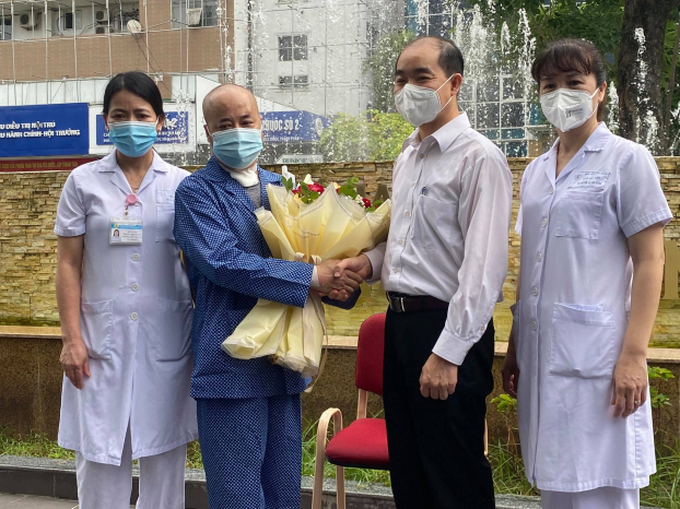   Ông Nguyễn Đình Hưng, Phó Giám đốc Sở Y tế Hà Nội và đại diện lãnh đạo Bệnh viện Thanh Nhàn trao hoa chúc mừng bệnh nhân COVID-19 khỏi bệnh  
