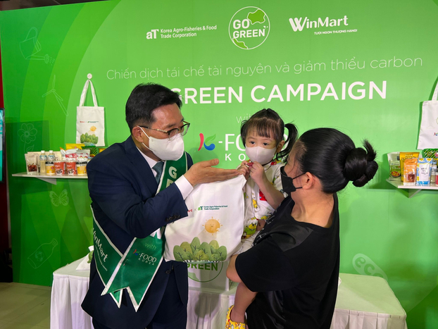   Ông Kim Choon Jin - Chủ tịch Công ty aT tặng quà cho khách hàng đến đổi pin trong chiến dịch Go Green with K-Food  