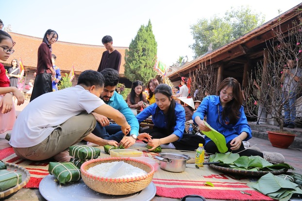 Du khách thích thú trải nghiệm gói bánh chưng...