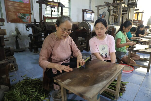 Bà Thuận hướng dẫn các em học sinh cách rút và vê sợi tơ từ thân sen