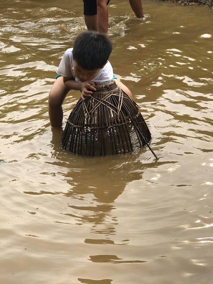 Cậu bé thích thú khi được tự mình cầm nơm úp cá trong hành trình Trải nghiệm một ngày làm nông dân tại Ba Vì. Ảnh: Phương Thanh