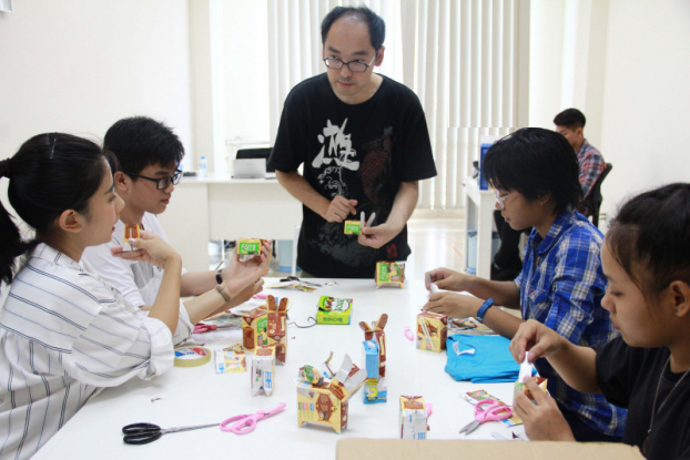   Nghệ nhân gấp giấy nổi tiếng Nhật Bản Kazuma Takahashi (giữa) năm thứ 3 tới Ngày hội Mottainai để hướng dẫn các em nhỏ làm đồ chơi tái chế từ bao bì các sản phẩm  