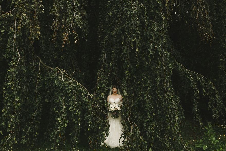 Cô dâu trong sắc váy trắng nổi bật giữa nền xanh của cây lá.