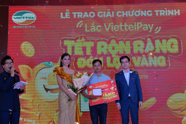   Ông Nguyễn Tiến Dũng- Phó Tổng Giám đốc Tổng Công ty Viễn thông Viettel và Hoa hậu Tiểu Vy (đại diện thương hiệu ViettelPay) trao thưởng cho khách hàng Nông Trung Hải trúng giải đặc biệt 1kg vàng  