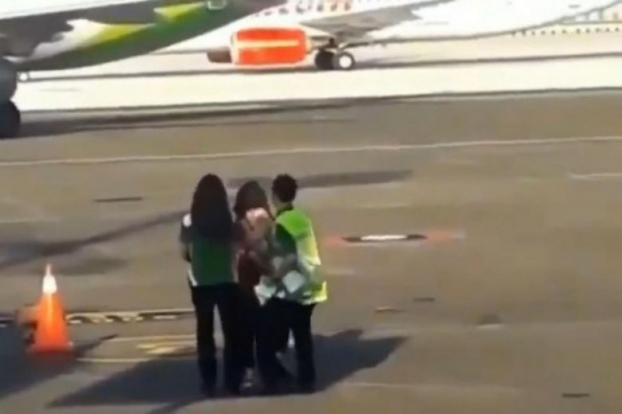   Hai nhân viên an ninh giữ người phụ nữ tại đường băng (Nguồn: Daily Mail)  