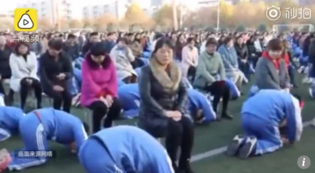   Ảnh cắt từ video cho thấy hàng ngàn học sinh đang đập đầu, quỳ gối (Ảnh: SCMP)  