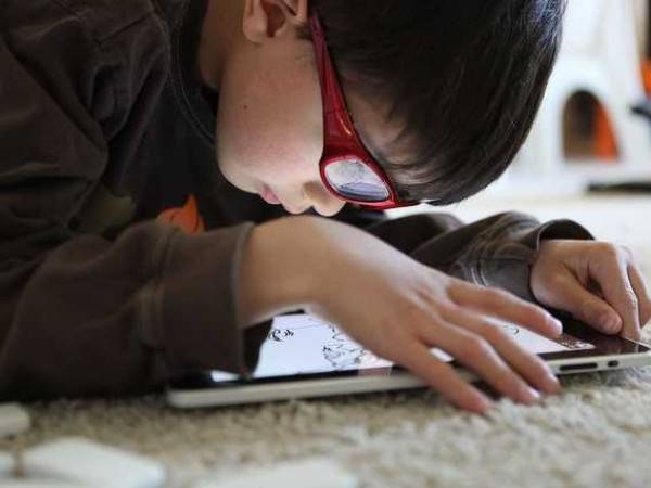 Trẻ thường xem ti vi, chơi máy vi tính, chơi điện thoại... là nguyên nhân cơ bản gây ra tật cận thị. Ảnh minh họa