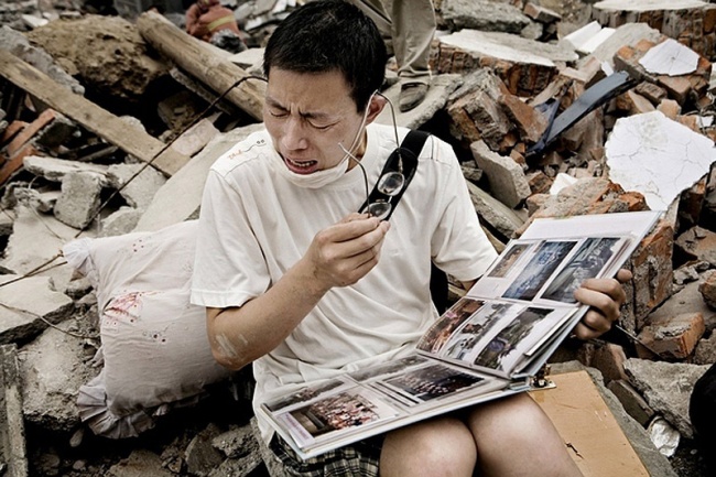 Một người đàn ông khóc sau khi tìm thấy album gia đình trong đống đổ nát của ngôi nhà của mình sau một trận động đất